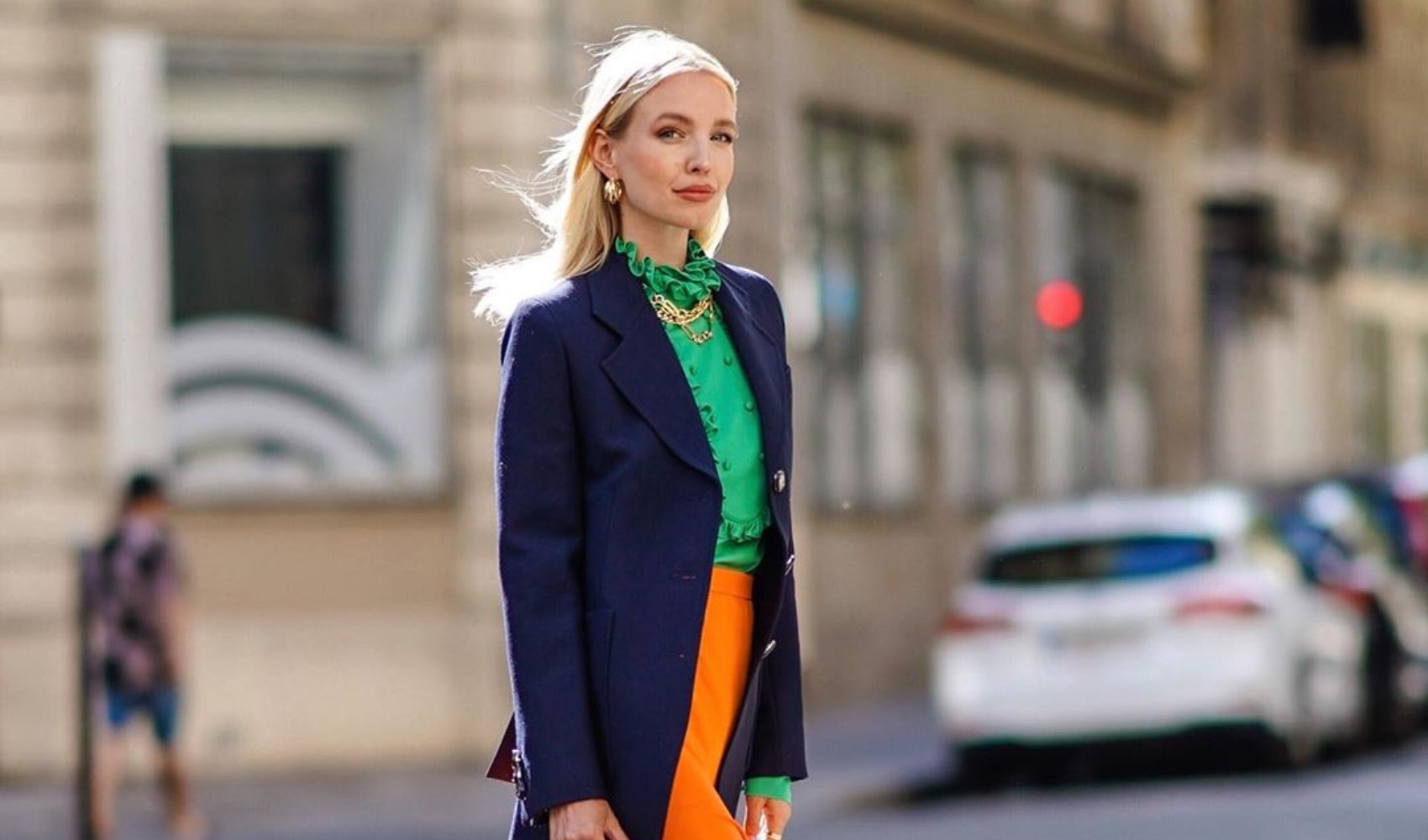 H Leonie Hanne περπατά με σακάκι και τοπ σε πράσινο κα φούστα σε πορτοκαλί