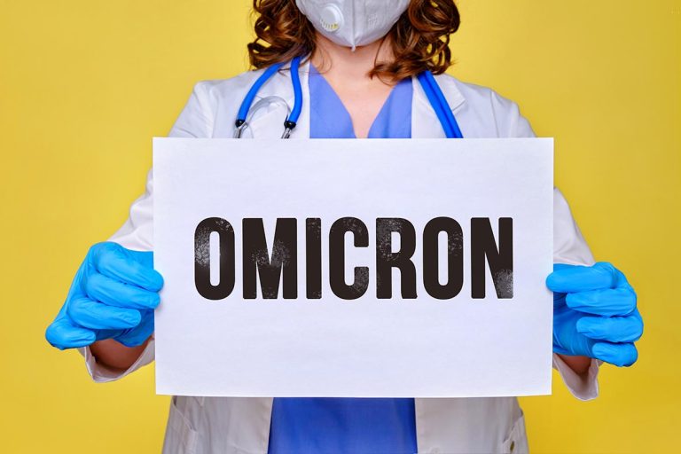 Γιατρός με μάσκα κρατά χαρτί που γράφει πάνω του OMICRON.