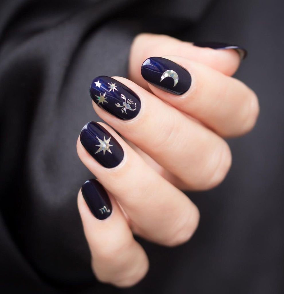 Νύχια βαμμένα σε σκούρο χρώμα με ζωδιακά θέματα πάνω τους