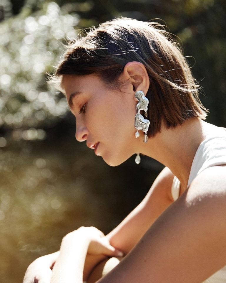 Γυναίκα με σκουλαρίκια δίπλα σε λίμνη κοντινό πλάνο σε προφίλ