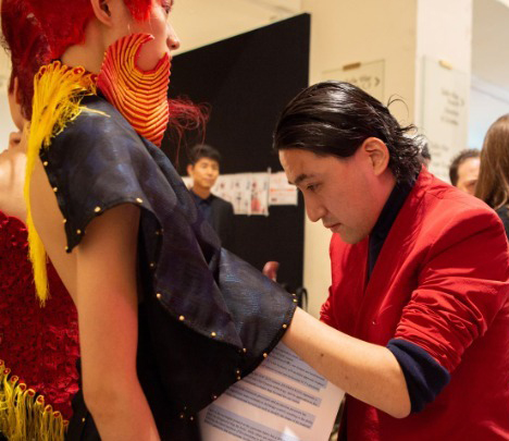 O Ιαπωνέζος σχεδιαστής Yuima Nakazato διορθώνει ένα ρούχο σε μοντέλο του