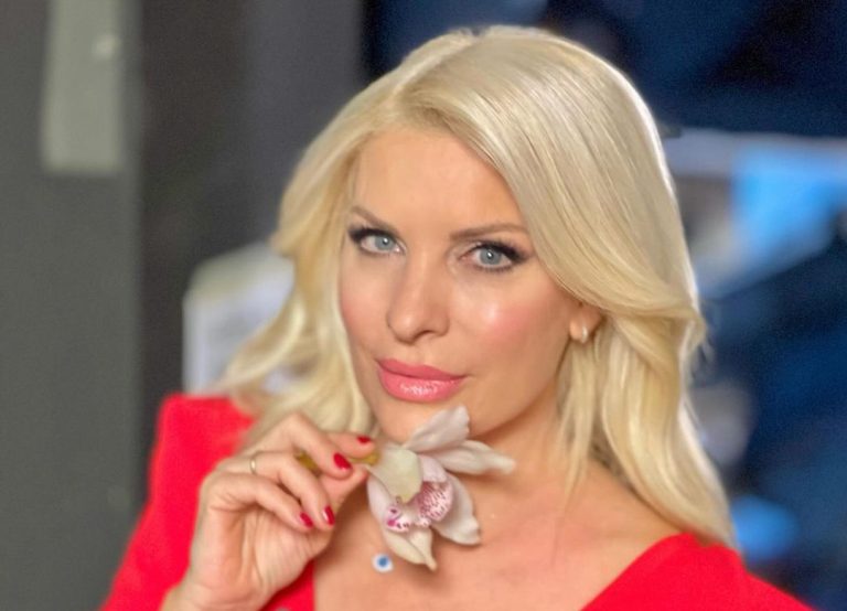 Η Ελένη Μενεγάκη στο πλατό της εκπομπής της με κόκκινο φόρεμα και λουλούδι στο λαιμό