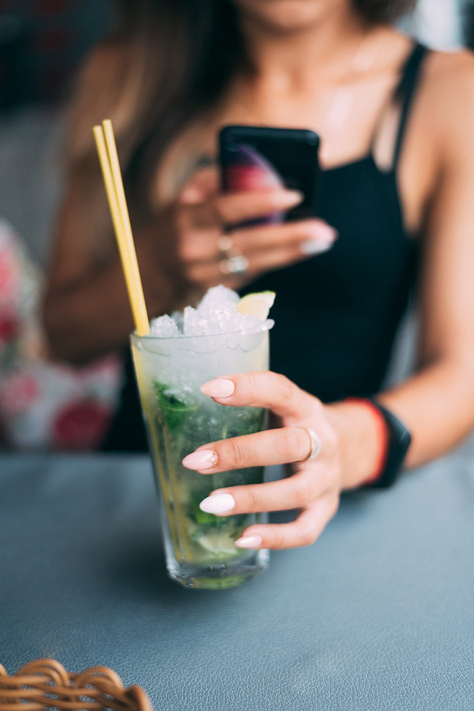 Γυναίκα σε μπαρ με ένα κοκτέιλ στο ένα χέρι της και το κινητό στο άλλο