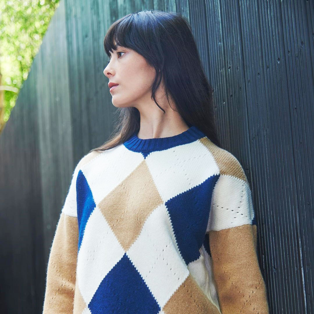 Μια νέα γυναίκα φοράει πουλόβερ με ρόμβους