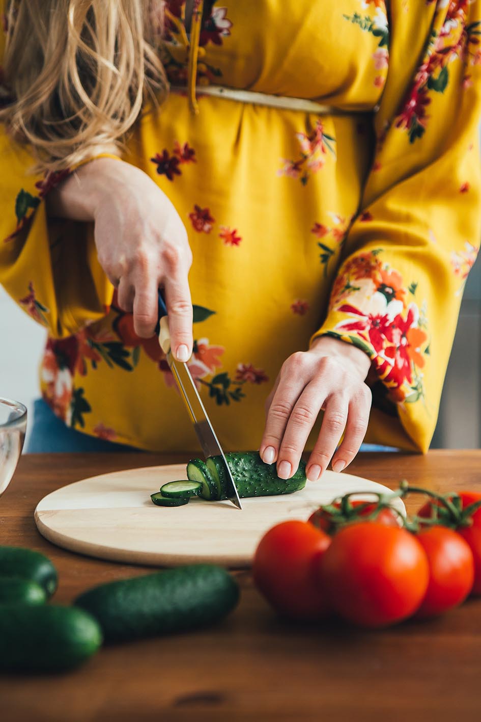 Χέρια κόβουν πάνω στον ξύλινο πάγκο λαχανικά