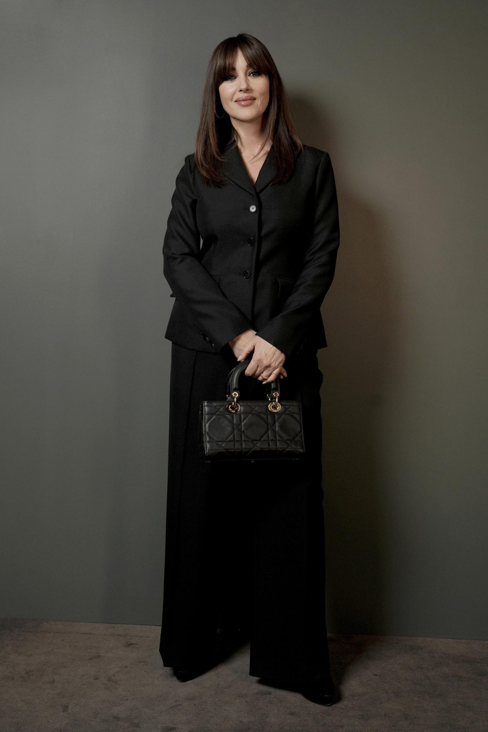 Η Monica Bellucci φόρεσε ένα μαύρο κοστούμι Dior και μια τσάντα Dior.