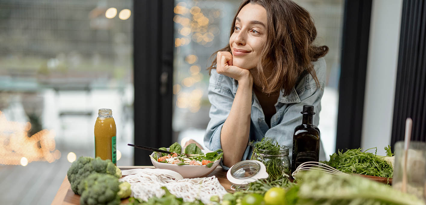 Γυναίκα με λαχανικά και σαλάτες πάνω σε τραπέζι