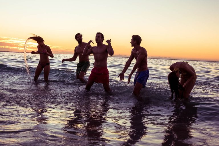 Φίλοι αγόρια κορίτσια διασκεδάζουν στη θάλασσα