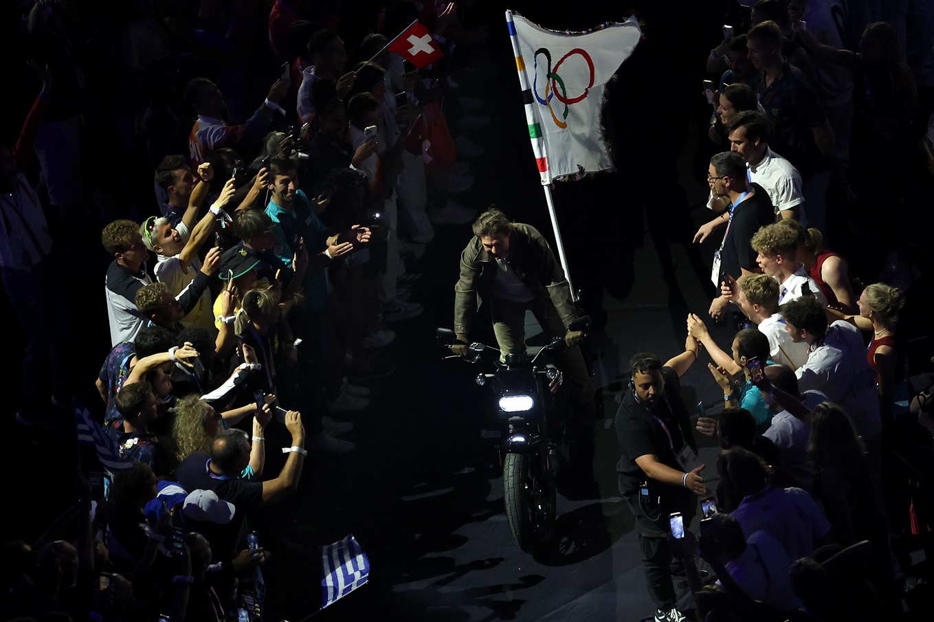 Ο Tom Cruise οδηγεί μια μοτοσικλέτα με την Ολυμπιακή σημαία κατά τη διάρκεια της Τελετής Λήξης των Αγώνων Παρίσι 2024 στο Stade de France
