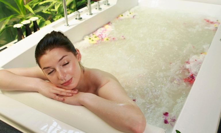 Γυναίκα ξαπλωμένη στη μπανιέρα απολαμβάνει το μπάνιο της