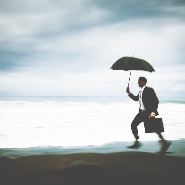 Άνδρας επαγγελματίας με ομπρέλα δίπλα στη θάλασσα