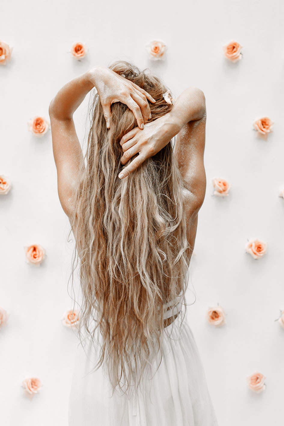 Γυναίκα με μακριά μαλλιά μας γυρνά την πλάτη της - τριαντάφυλλα στον τοίχο