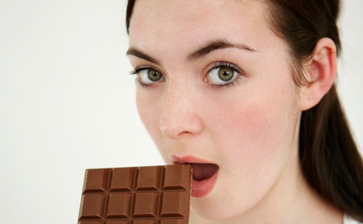 Στη φωτογραφία γυναίκα τρώει σοκολάτα. Πόσο υγιεινή είναι τελικά η μαύρη σοκολάτα ή είναι απλώς μια άλλη μορφή ζάχαρης.