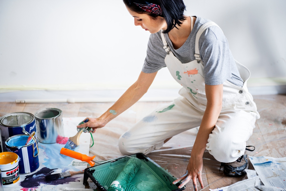 γυναίκα με στολή εργασίας βάφει τους τοίχους του σπιτιού της