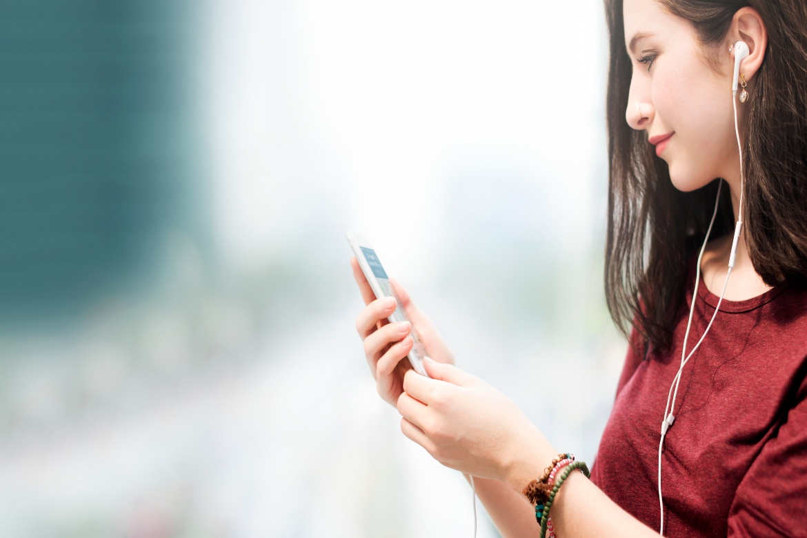 νεαρή γυναίκα περπατάει και κοιτάζει το κινητό της