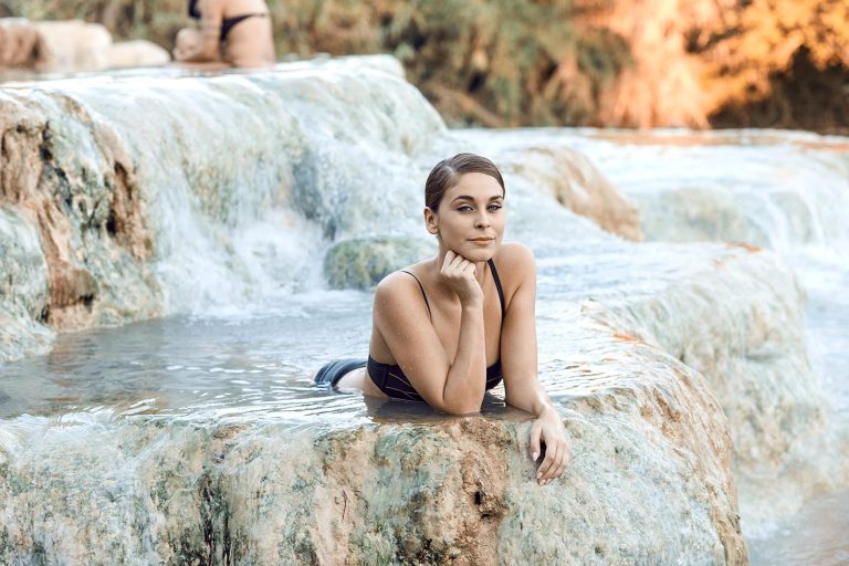 Γυναίκα κάνει μπάνιο σε φυσική πισίνα με βράχια