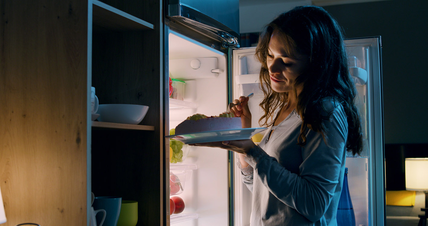 Γυναίκα τρώει το βράδυ μπροστά στο ψυγείο