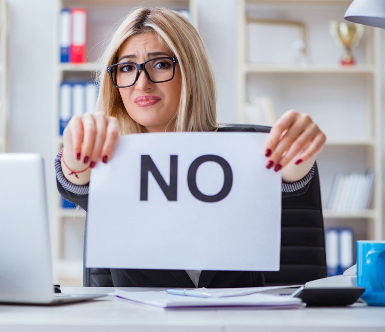 Γυναίκα στο γραφείο της κρατά χαρτί με τη λέξη Οχι