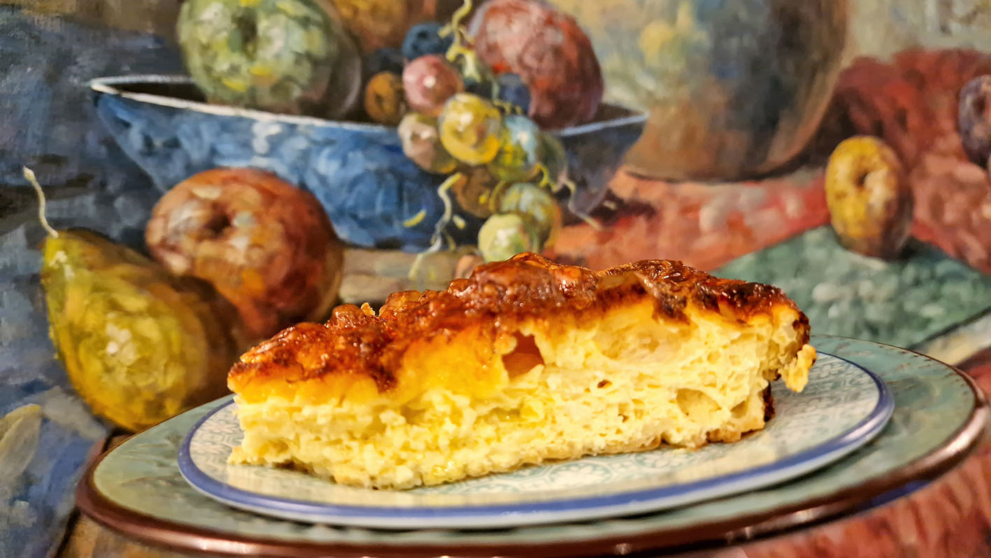 Συνταγή Τυρόπιτα σουφλέ κομμάτι σε πιάτο μπορστά από πίνακα