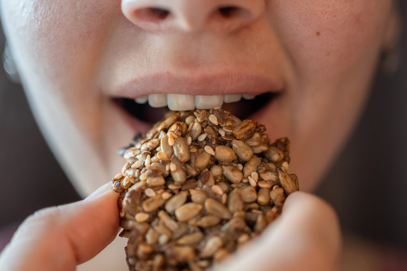 Κοντινό στα χείλια γυναίκας που τρώει μπισκότο υγιεινό με μπανάνα και seeds χωρίς γλουτένη