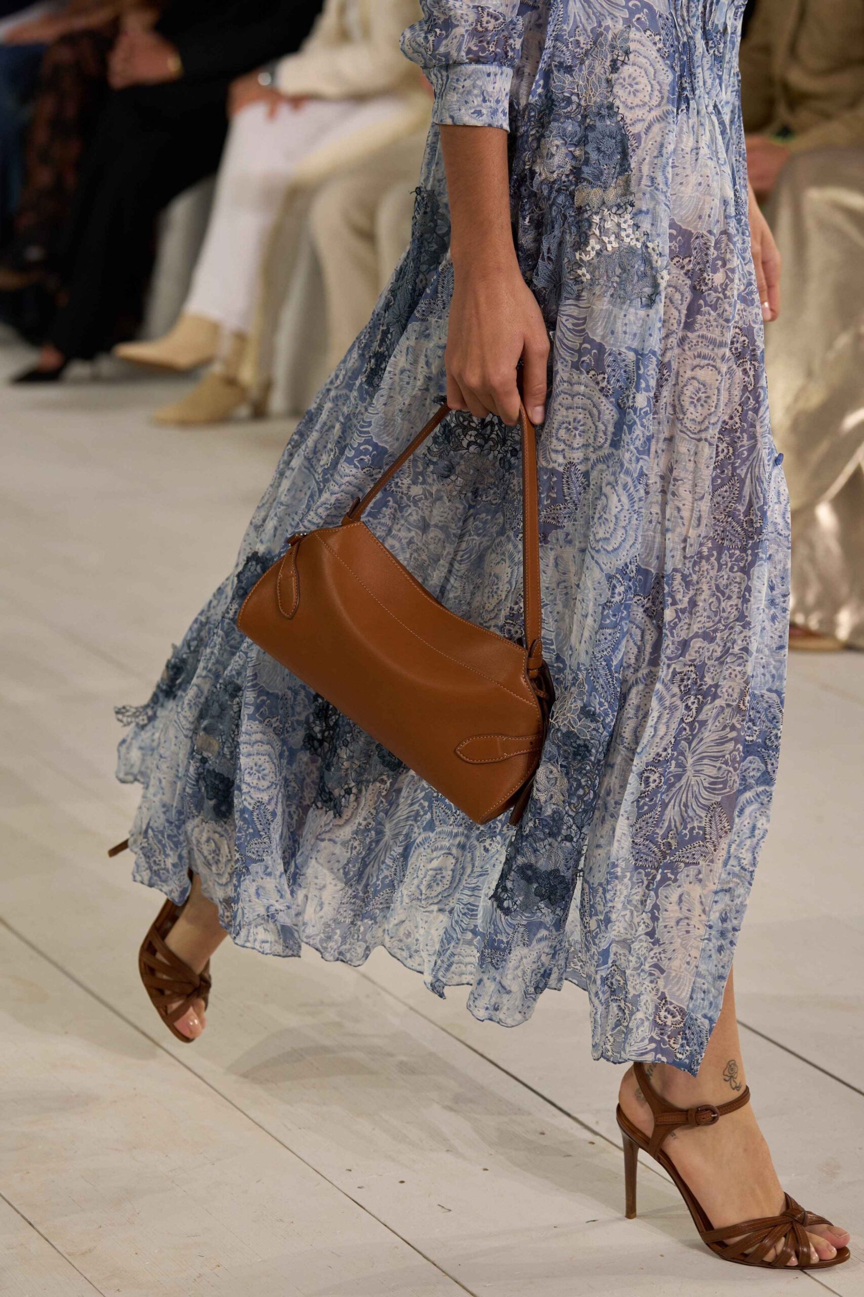 Μοντέλο περπατά φορώντας σύνολο Ralph Laurent από τη συλλογή Άνοιξη/Καλοκαίρι 2025 κρατώντας τσάντα
στο χρώμα mocha mousse.