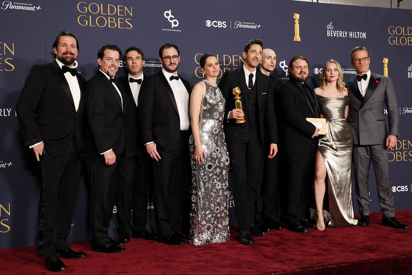 To καστ της ταινίας The Brutalist που σάρωσε τα βραβεία, από αριστερά προς τα δεξιά: ο Trevor Matthews, καλεσμένος,, ο Brian Young, καλεσμένος, η Felicity Jones, ο Adrien Brody, ο μεγάλος νικητής των φετινών βραβείων για Best Performance σε Drama, o Daniel Blumberg, o Brady Corbet, η Mona Fastvold και ο Guy Pearce.