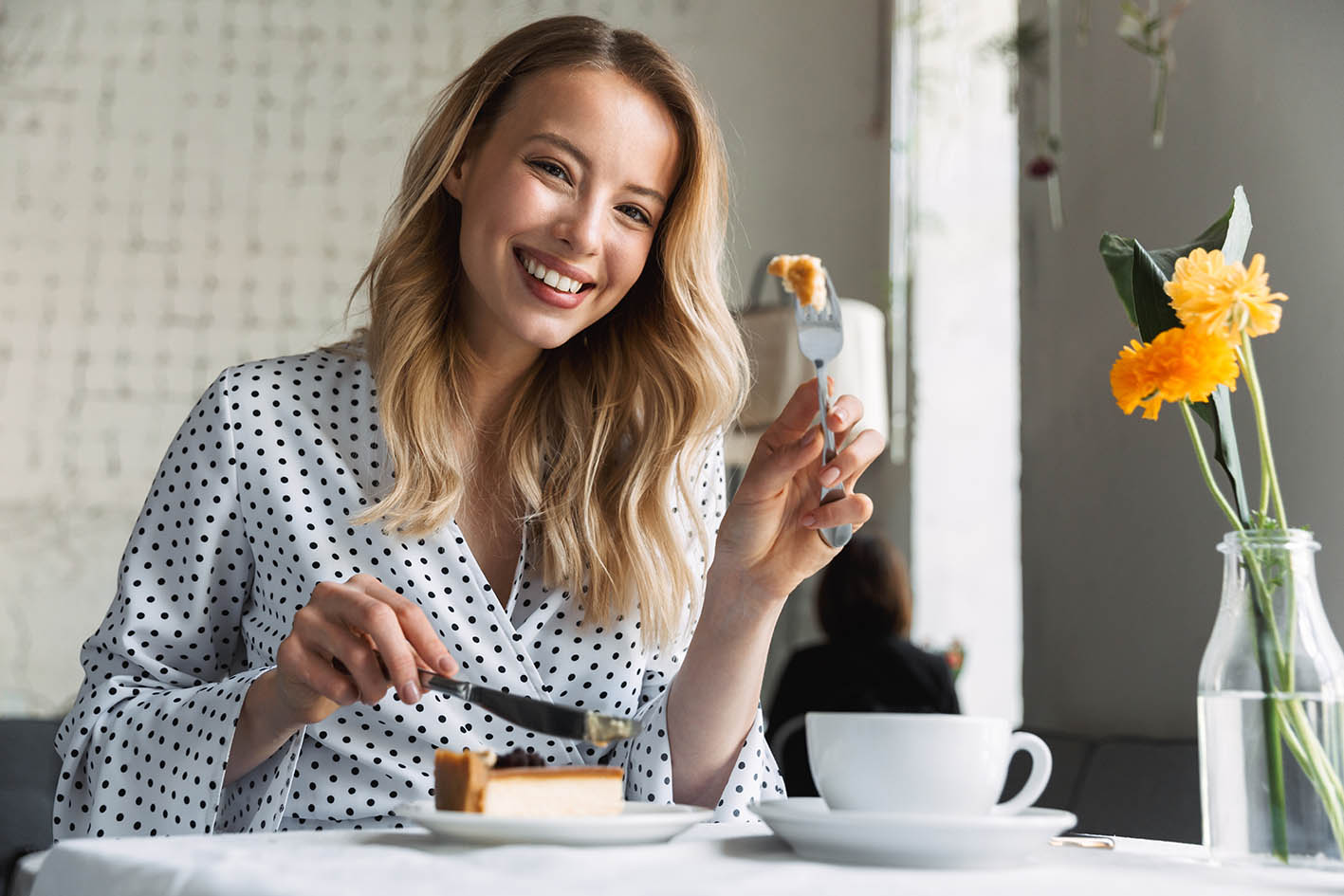 Γυναίκα πίνει καφέ και τρώει γλυκό