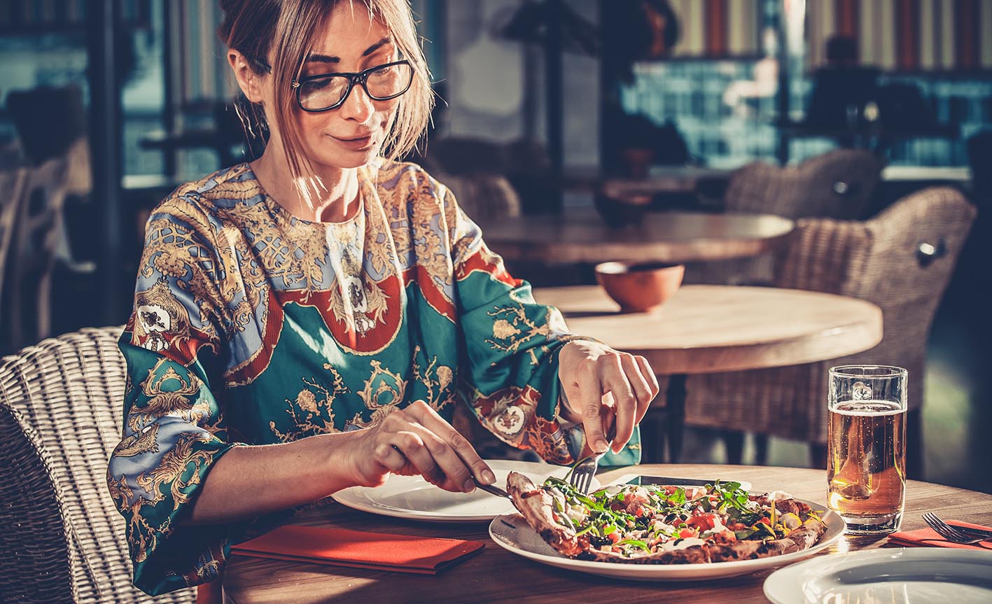 Γυναίκα σε εστιατόριο κόβει ένα κομμάτι πίτσα για να το φάει