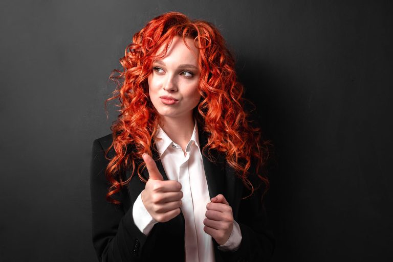 Κοκκινομάλα γυναίκα κάνει το σήμα της επιτυχίας χαρούμενη