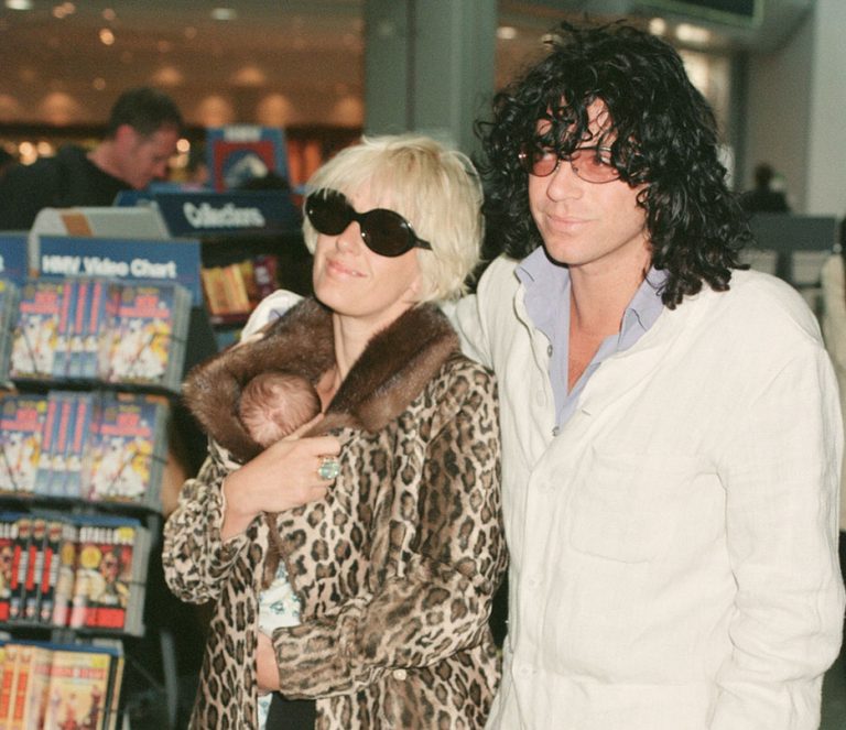 Η Paula Yates και ο φίλος της, ο τραγουδιστής των INXS Michael Hutchence φεύγουν από το αεροδρόμιο Heathrow για το Χονγκ Κονγκ. Η Paula κρατά την κόρη τους Heavenly Hiraani Tiger Lily (γεννημένη στις 26 Ιουλίου 1996). Ο Michael Hutchence πέθανε στις 22 Νοεμβρίου 1997 και η Paula Yates πέθανε στις 27 Σεπτεμβρίου 2000. H φωτογραφία είναι από τις 12 Σεπτεμβρίου1996.