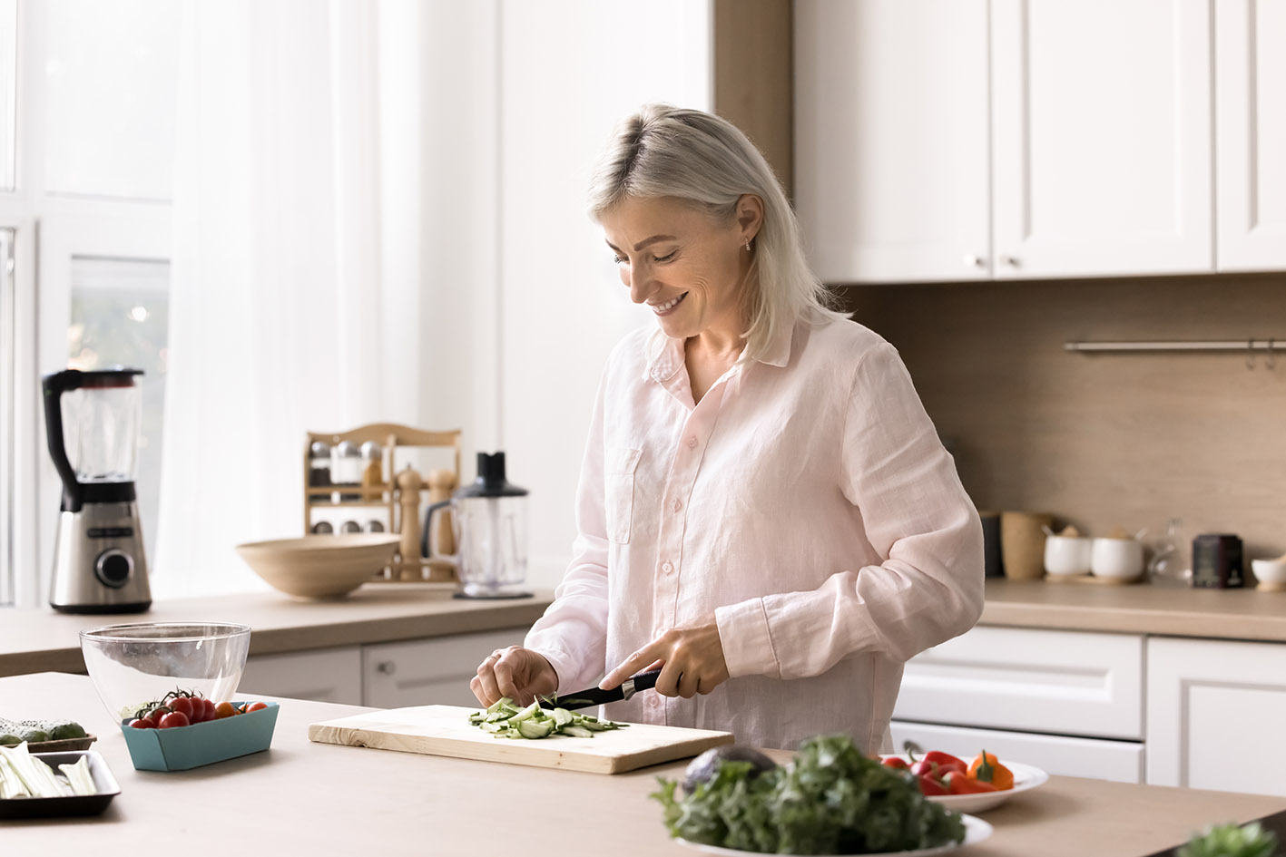 Xαρούμενη γυναίκα με γκρι μαλλιά ετοιμάζει σαλάτα