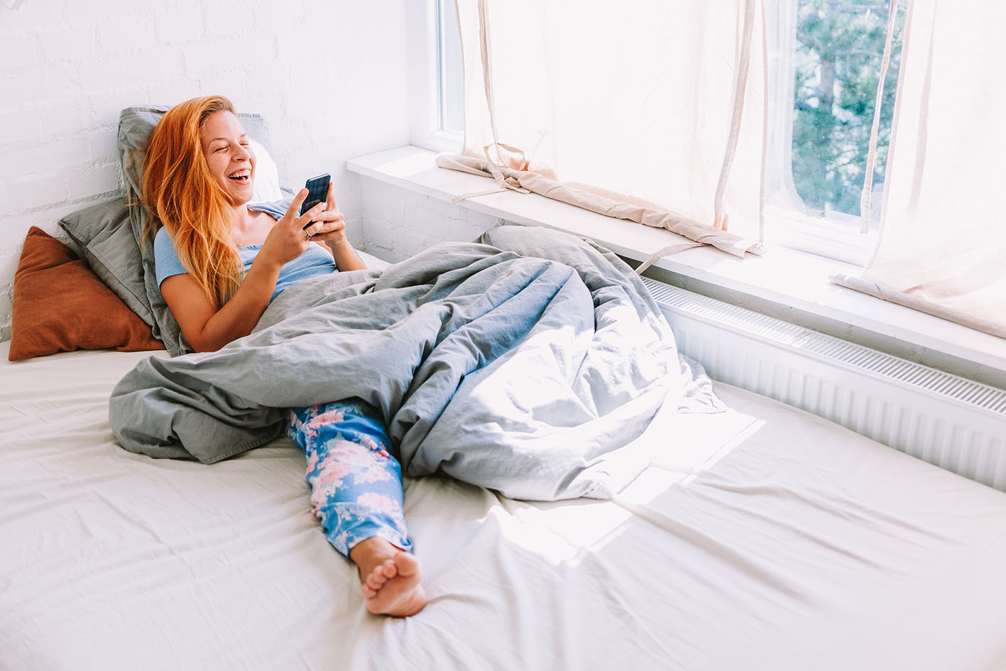 Γυναίκα γελά βλέποντας κάτι στο κινητό της