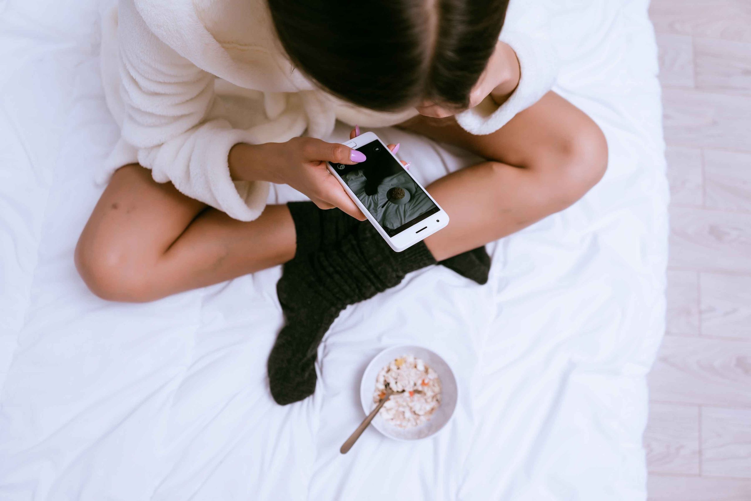 Γυναίκα στο κρεβάτι με κινητό φωτογραφίζει πρωινό