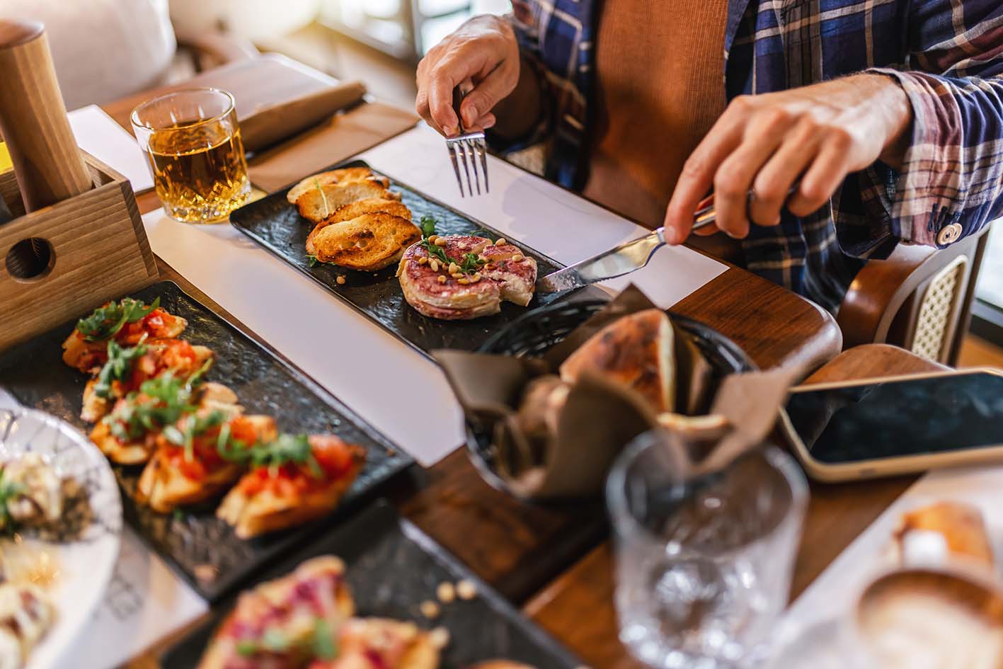 Άνδρας τρώει κρέας φαίνονται τα χέρια του και το φαγητό