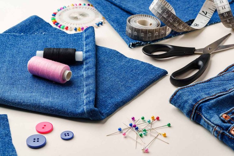 Είδη ραπτικής και ύφασμα τζιν τοποθετημένα σε χώρο εργασίας για μεταποιήσεις ρούχων σε φωτεινό περιβάλλον από κοντά