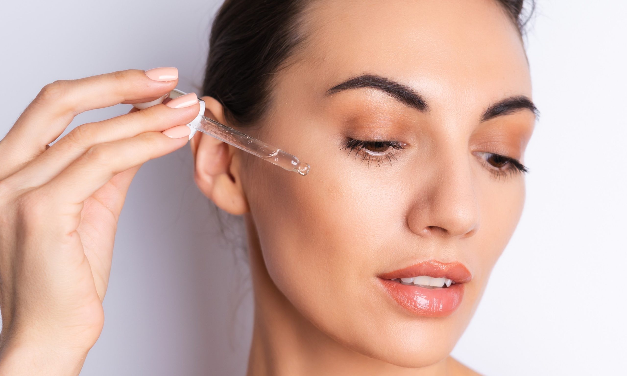 Γυναίκα βάζει ορό στο πρόσωπό της με σταγονόμετρο.