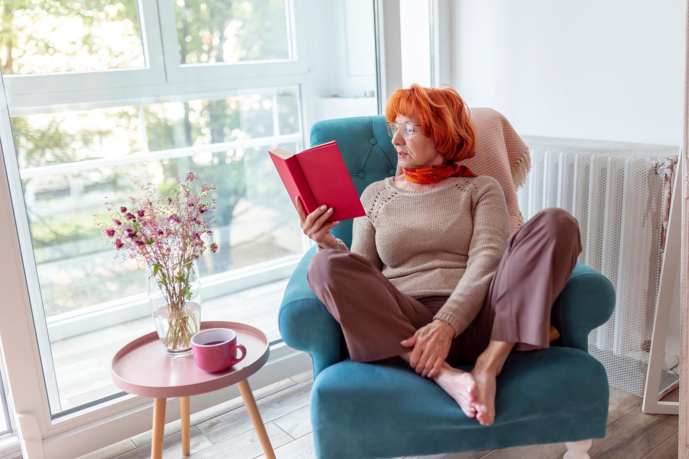 Γυναίκα μέσης ηλικίας διαβάζει βιβλίο σε πολυθρόνο