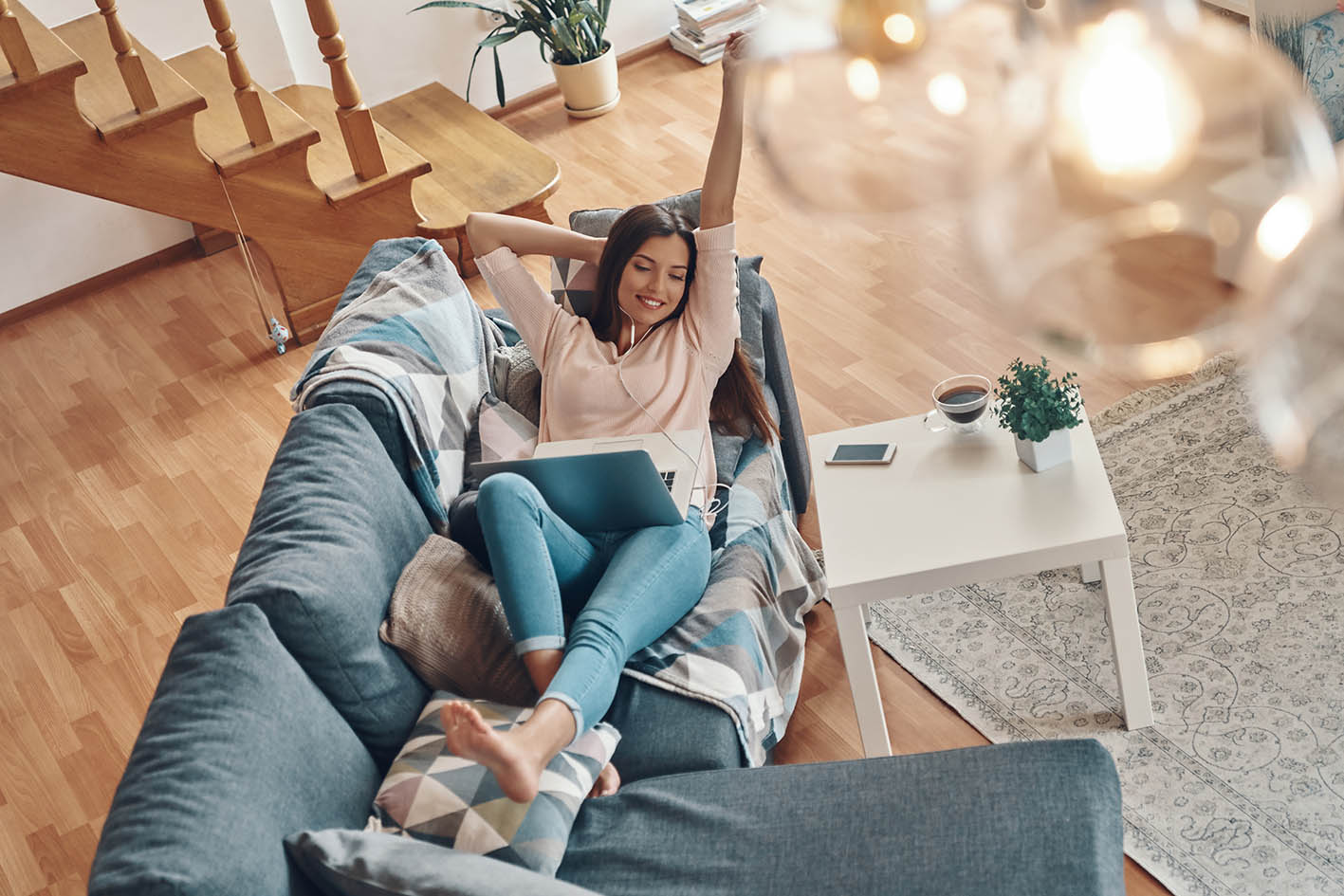 Γυναίκα σε καναπέ με κομπιούτερ στα πόδια