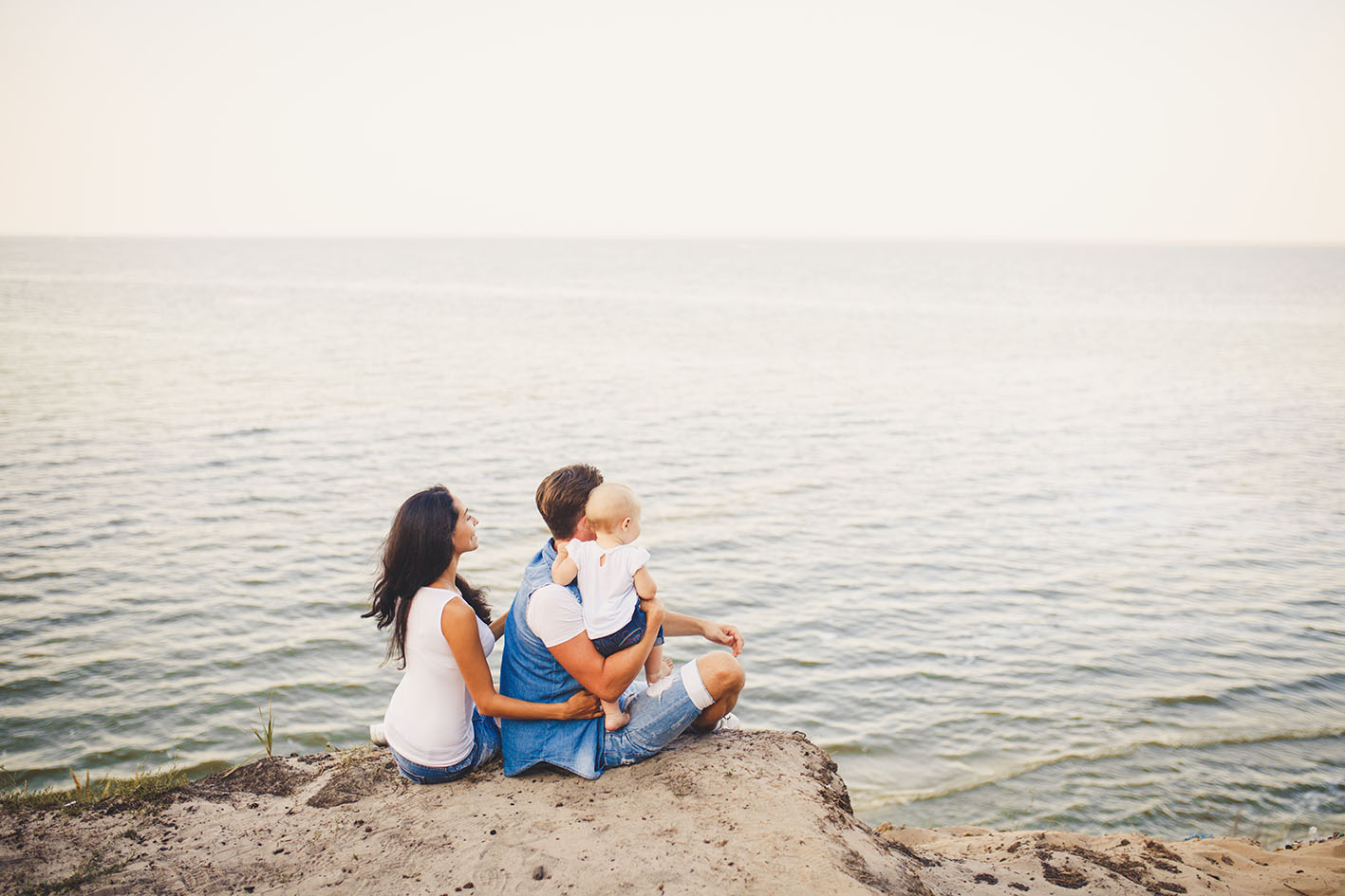Ζευγάρι με το παιδάκι τους στα βράχια δίπλα στη θάλασσα αγναντεύουν