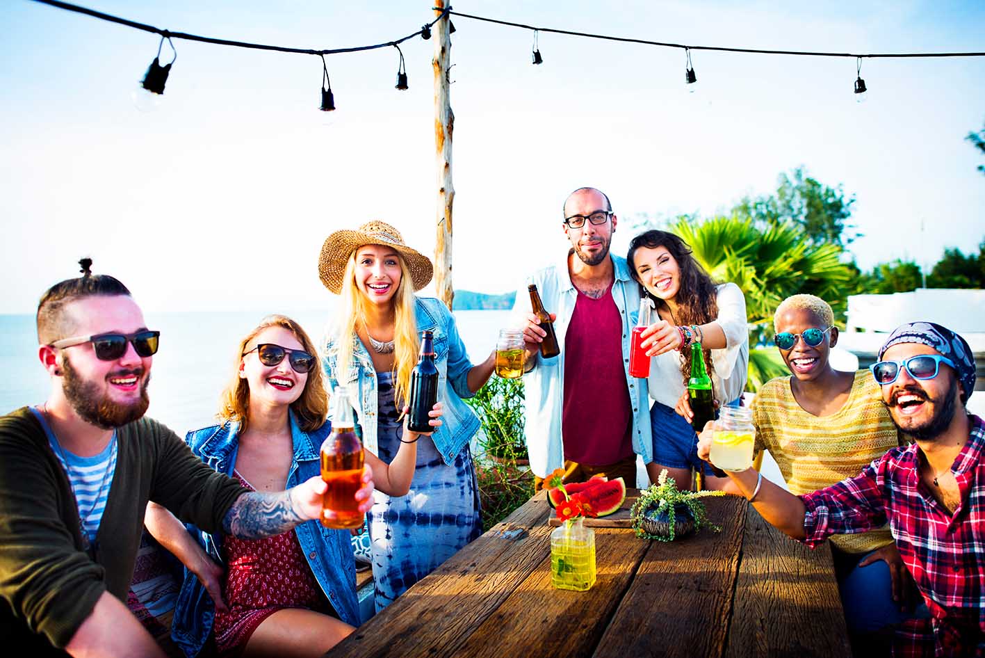 Φίλοι διασκεδάζουν πίνοντας δίπλα στη θάλασσα