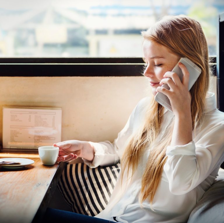 Γυναίκα μιλά στο κινητό τηλέφωνο και πίνει καφέ