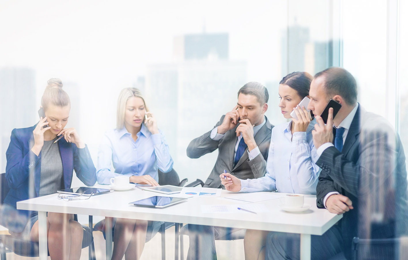 Συνάδελφοι στο γραφείο με τα κινητά τους μιλούν με αυτά και μεταξύ τους
