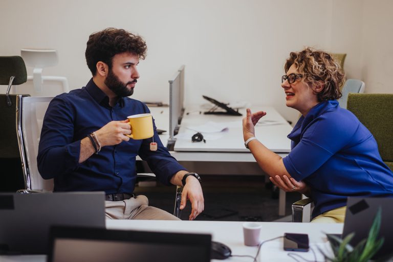Συνάδελφοι μιλάνε στο γραφείο πίνοντας καφέ