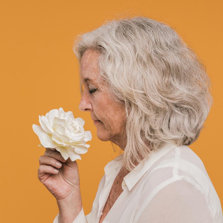 Γυναίκα μέσης ηλικίας μυρίζει λουλούδι λευκό