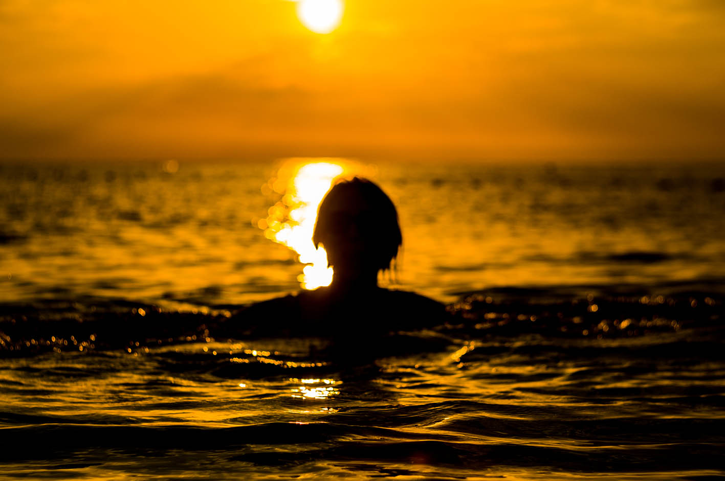Γυναίκα κολυμπά στη θάλασσα το ηλιοβασίλεμα