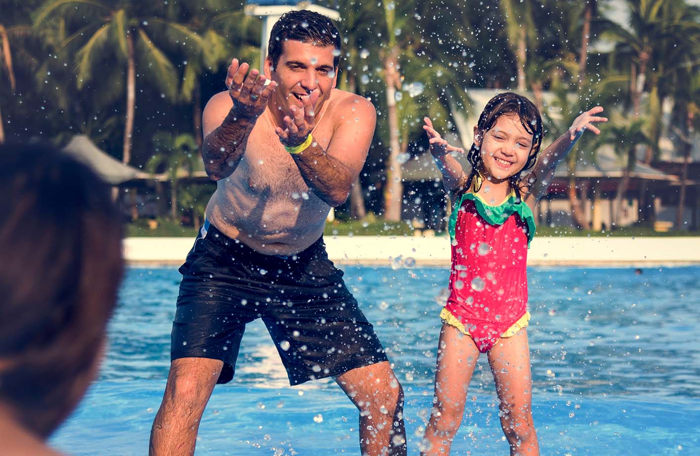 Πατέρας και κόρη πιτσιλάνε νερό από πισίνα και χαίρονται σε υδάτινο πάρκο