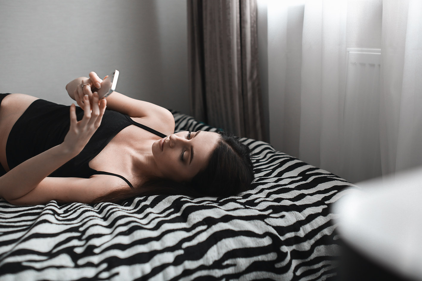 Γυναίκα νέα σκρολάρει στο κρεβάτι της