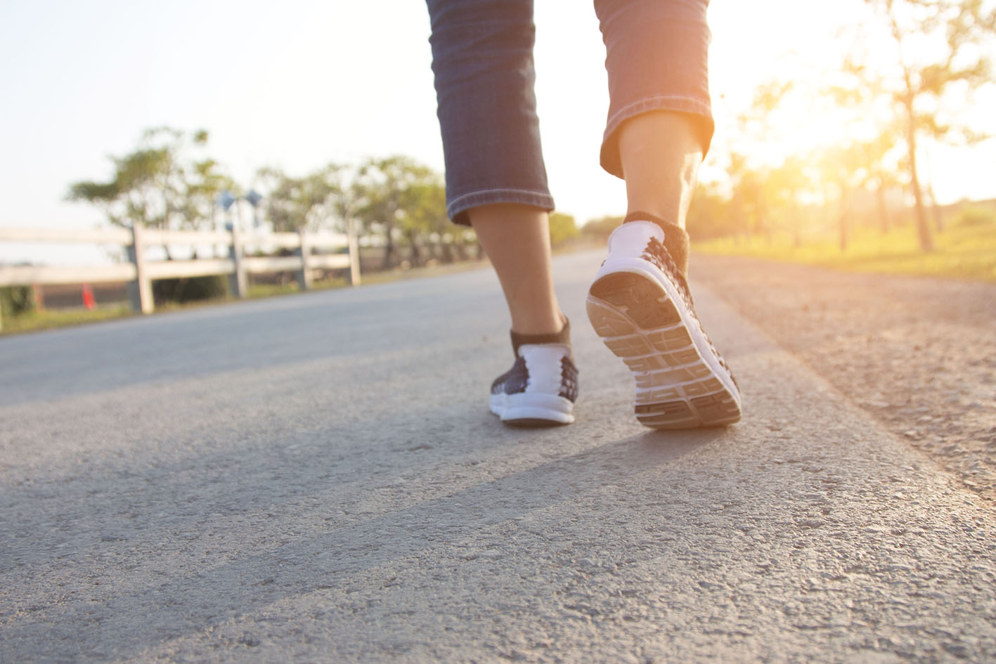 Γυναικεία πόδια με αθλητικά περπατά λίγο πριν τη δύση του ήλιου