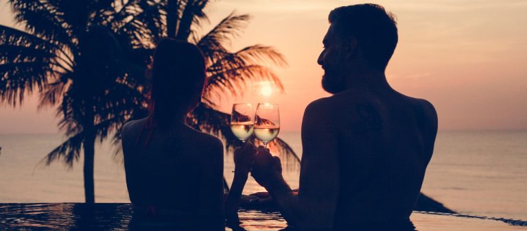 Καλοκαιρινός έρωτας, ζευγάρι πίνει κρασί μέσα σε πισίνα