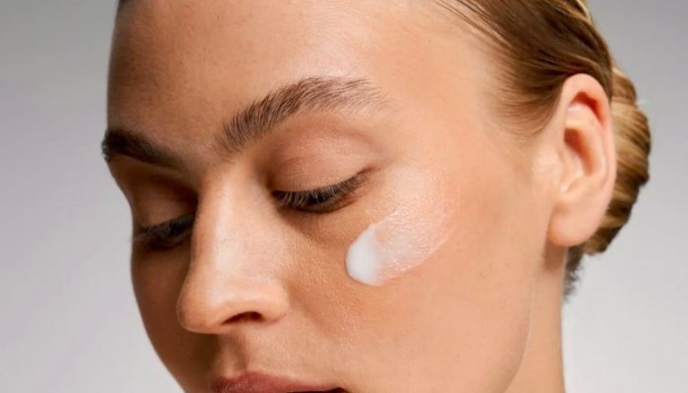 Γυναίκα με καθαρό πρόσωπο και κρέμα στο μάγουλο
